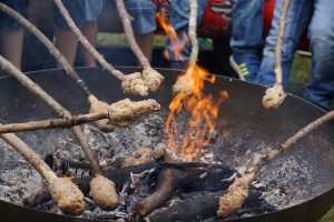 Kinder lieben das Stockbrotrösten am Feuer.