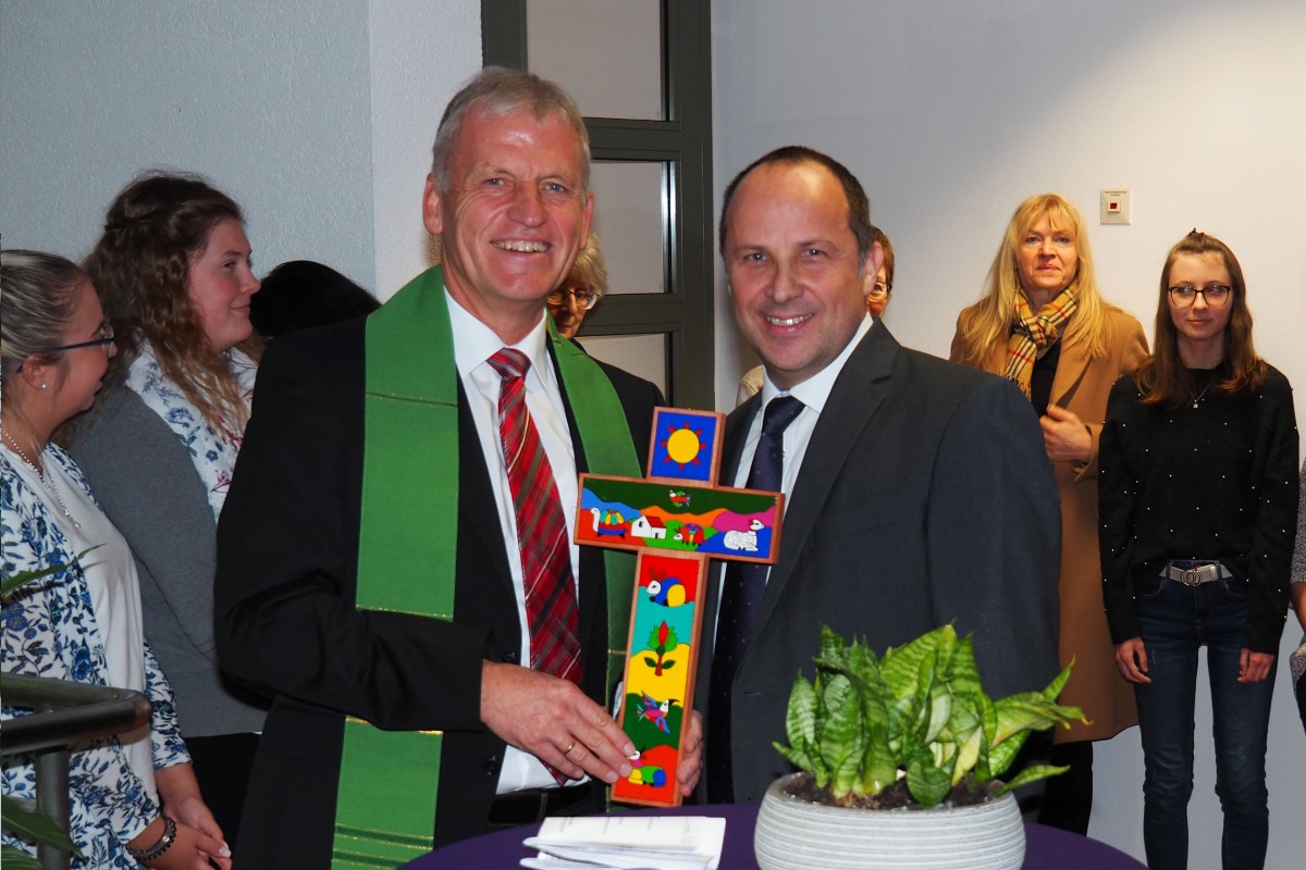 Dekan Peter Bertram (links) überreicht Vorstand Andreas Karau ein Kreuz für die neue Geschäftsstelle.