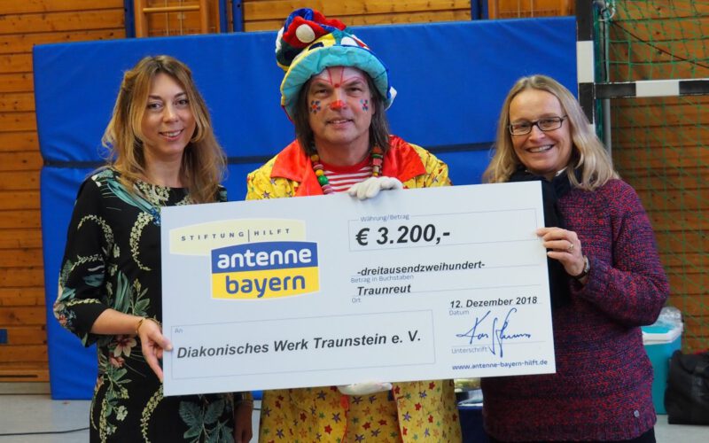 Felicitas Hönes (links) und Clown Lupino überreichen Margarete Winnichner einen Spendenscheck über 3200 Euro.