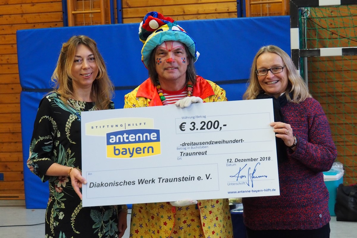 Felicitas Hönes (links) und Clown Lupino überreichen Margarete Winnichner einen Spendenscheck über 3200 Euro.