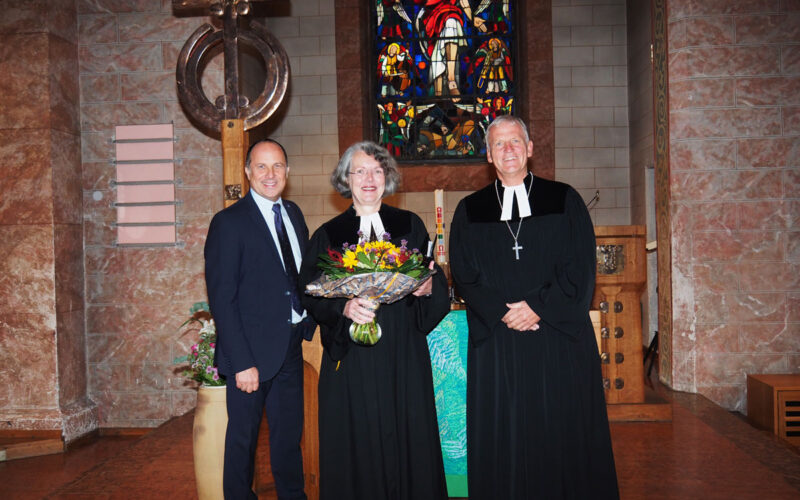 Dekan Peter Bertram (rechts) und Diakonievorstand Andreas Karau bedanken sich bei Gastpredigerin Barbara Hauck mit einem Blumenstrauß.