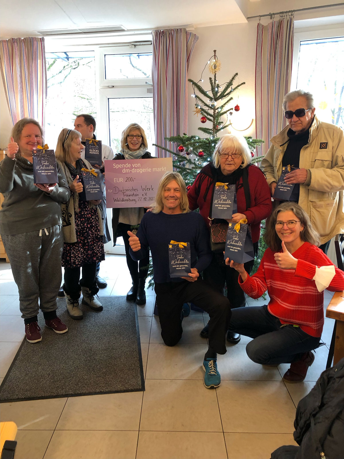 Besucher und Mitarbeitende des Tageszentrums Waldkraiburg freuen sich über die Weihnachtsgeschenke