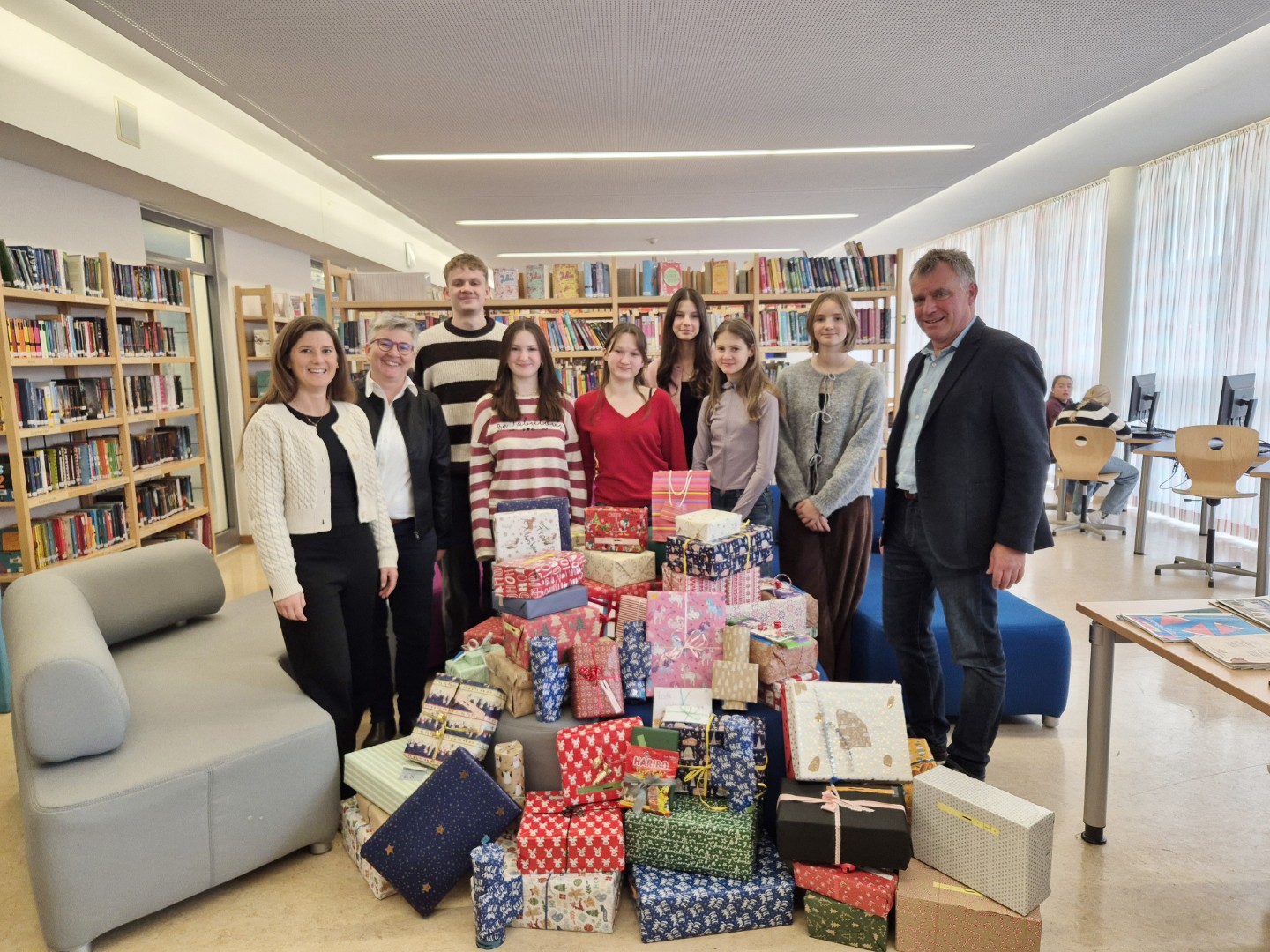 Von rechts: Schulleiter Diether Thumser freut sich gemeinsam mit den Schülerinnen und Schülern, Oberstudienrätin Ute Heim und der stellvertretenden Heimleiterin Elisabeth Brich über 71 Weihnachtsgeschenke für Kinder und Jugendliche des Wilhelm-Löhe-Heims Traunreut.