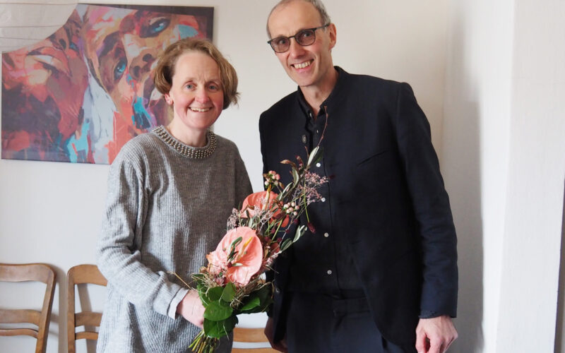 Diakon Michael Sörgel, Fachbereichsleiter Soziale Dienste, begrüßt Alexandra Karl zum Arbeitsbeginn mit einem Blumenstrauß.