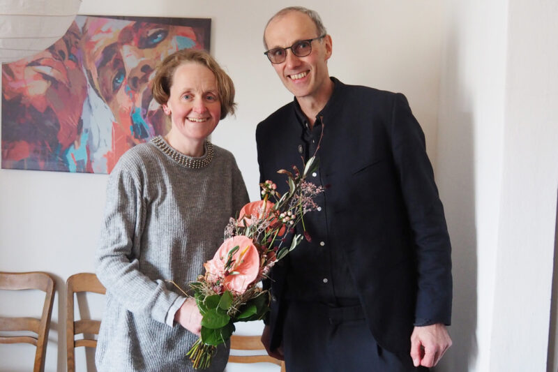 Diakon Michael Sörgel, Fachbereichsleiter Soziale Dienste, begrüßt Alexandra Karl zum Arbeitsbeginn mit einem Blumenstrauß.