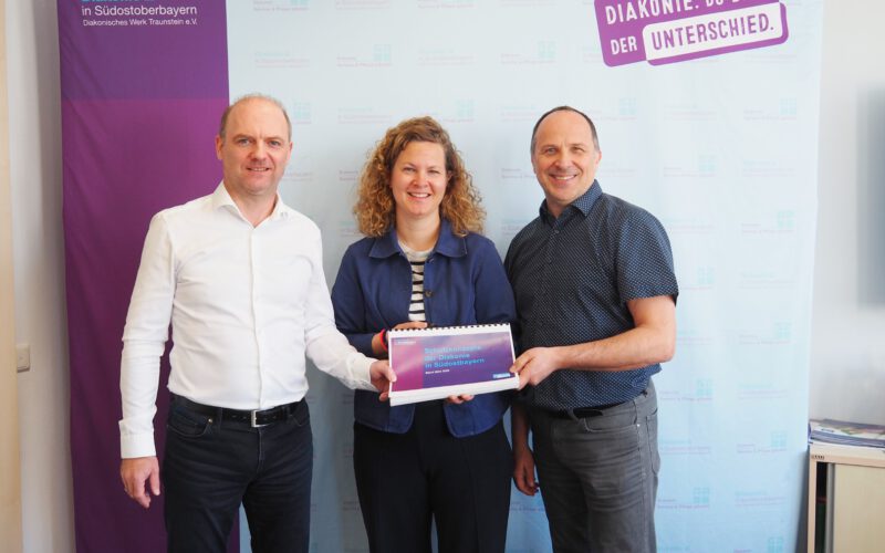 Julia Buchhorn, Präventionsbeauftragte der Geschäftsstelle, überreicht die gebündelten Schutzkonzepte an die Vorstände Andreas Karau (rechts) und Martin Schmid.