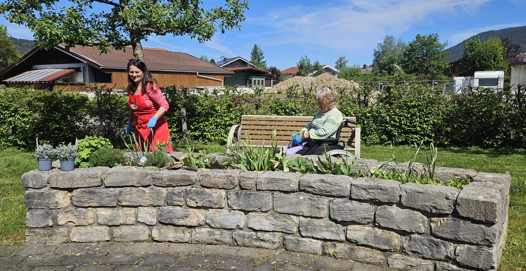 Eine Bewohnerinnen bepflanzt gemeinsam mit einer Mitarbeiterin das Hochbeet im Garten des Chiemgau-Stift Inzell.
