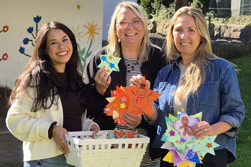 250 Sterne, die Wünsche wahr werden lassen: Maike Zimmermann, Geschäftsbereichsleiterin der Kindertagesstätten, und Melanie Janisch von „Spenden und Helfen“ überreichen Birgit Sailer von Vergissmeinnicht Chiemgau e.V. die liebevoll und farbenfroh gestalteten Sterne für die diesjährige Wunschbaumaktion.