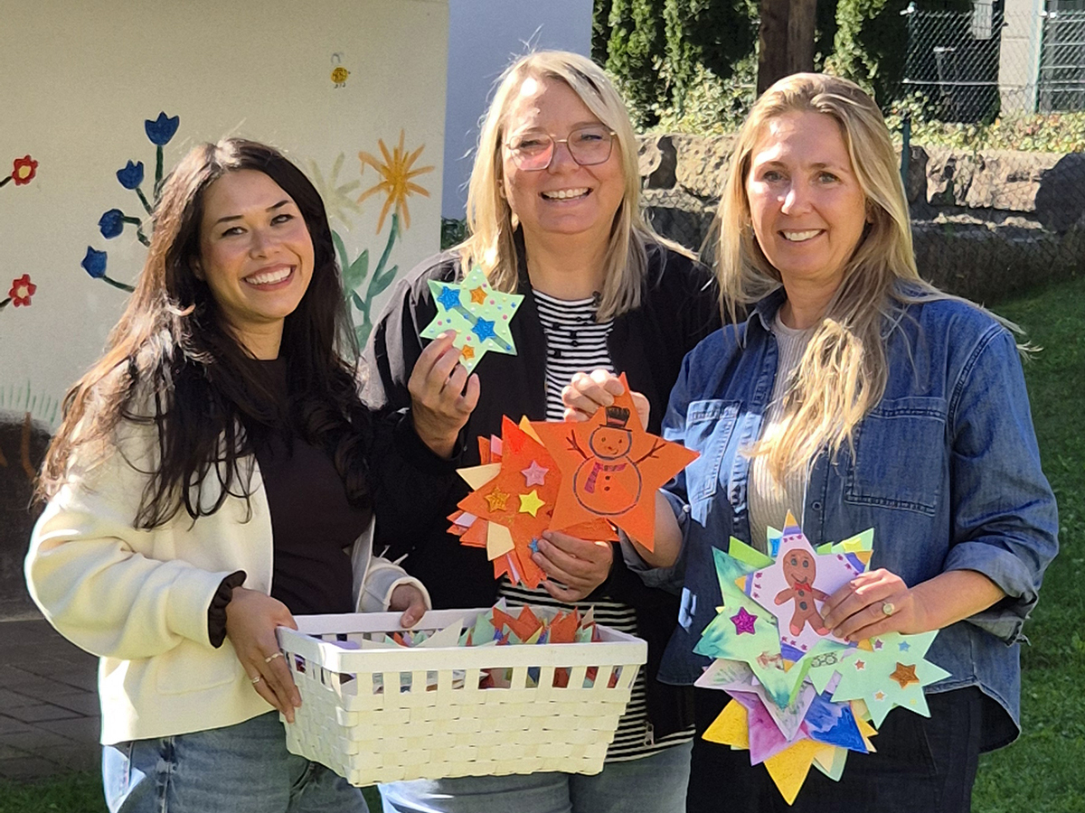 250 Sterne, die Wünsche wahr werden lassen: Maike Zimmermann, Geschäftsbereichsleiterin der Kindertagesstätten, und Melanie Janisch von „Spenden und Helfen“ überreichen Birgit Sailer von Vergissmeinnicht Chiemgau e.V. die liebevoll und farbenfroh gestalteten Sterne für die diesjährige Wunschbaumaktion.